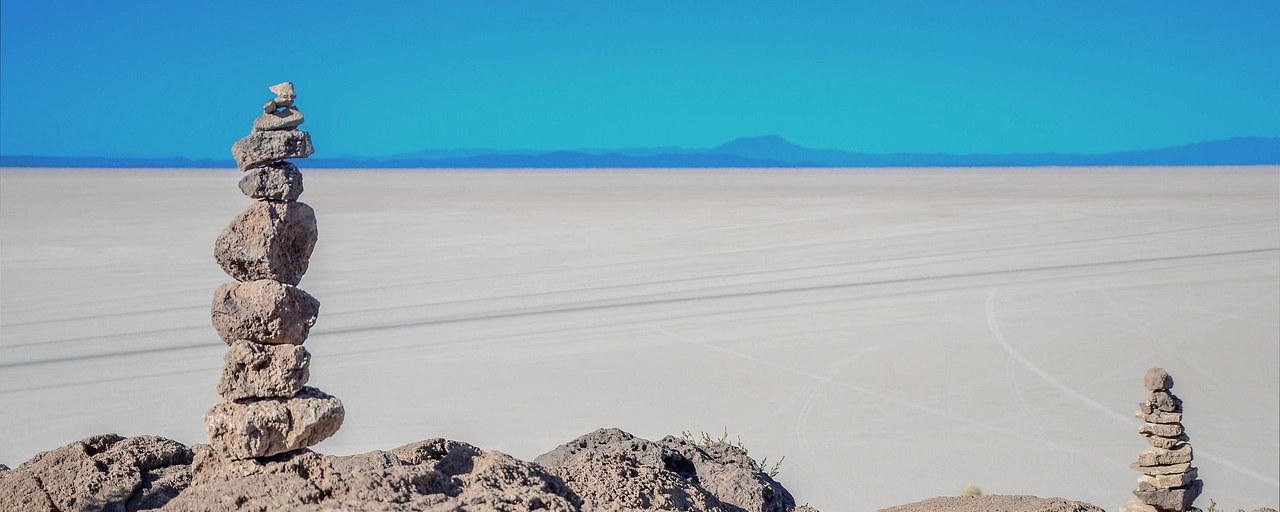 Stone cairns overlooking the vast Salar de Uyuni salt flats in Bolivia.