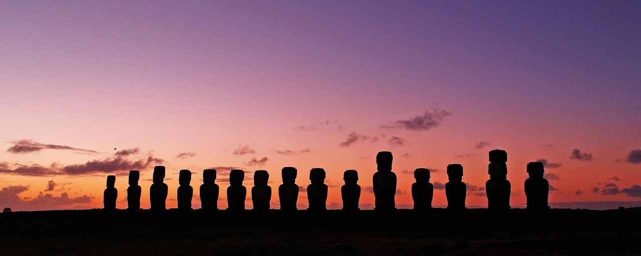 Moai statues silhouetted at sunset on Easter Island, Chile.
