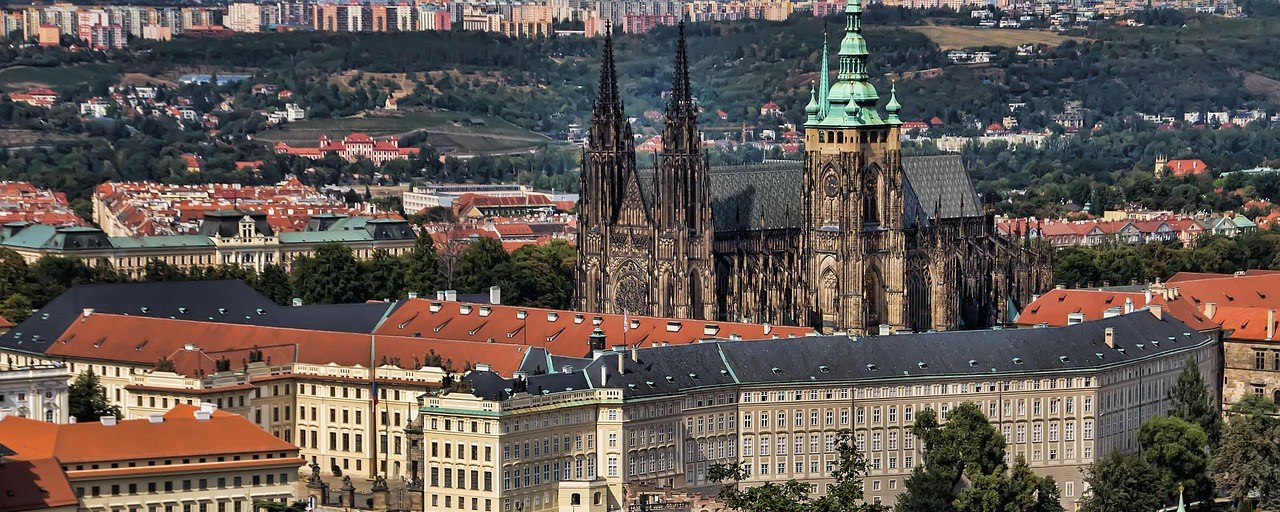 Prague Castle and Saint Vitus Cathedral above red rooftops in Czechia.