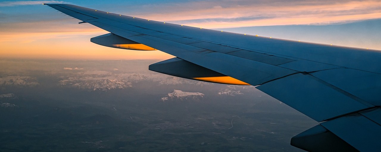Airplane wing above clouds at sunset