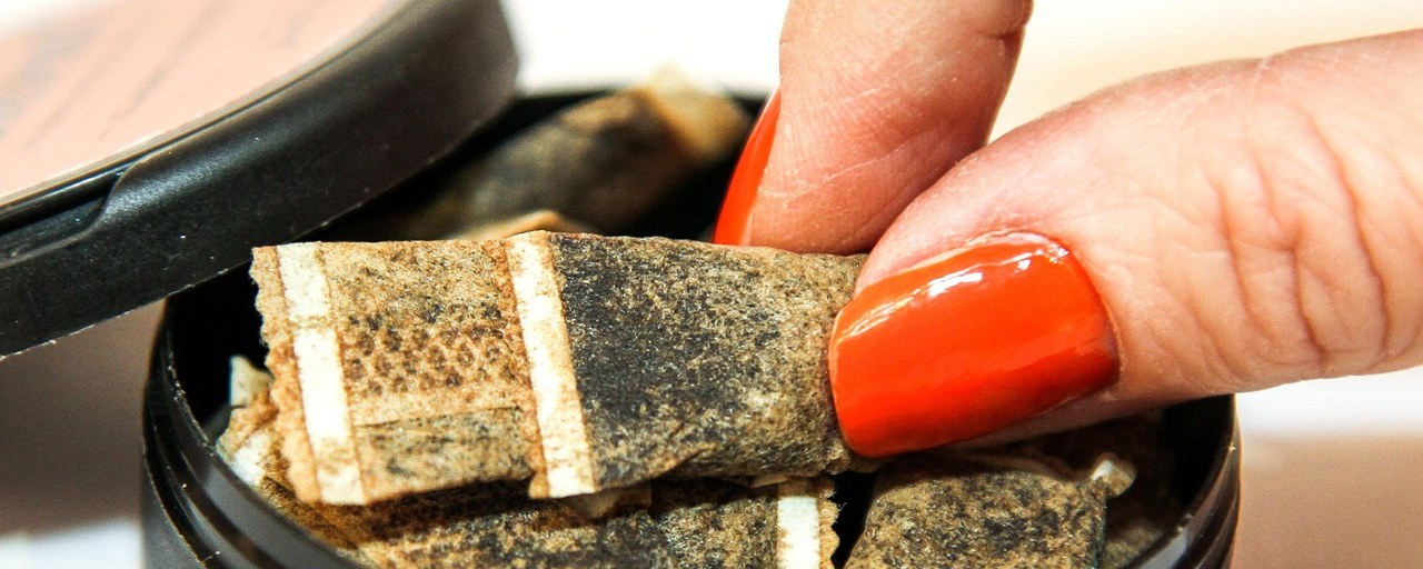 Hand lifting a snus portion from an open unbranded container