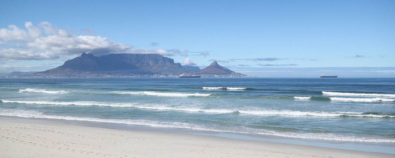 Table Mountain across the ocean from a sandy beach