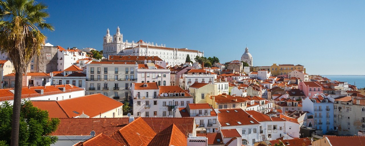 Lisbon rooftops and churches beneath a blue sky