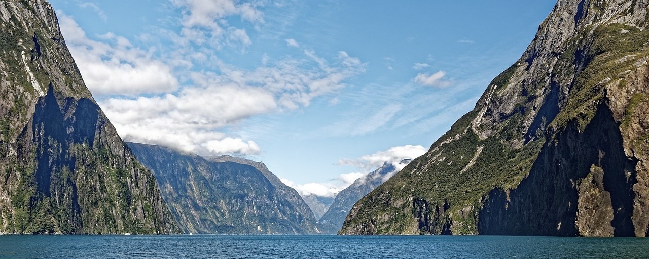Steep green mountains bordering Milford Sound in New Zealand